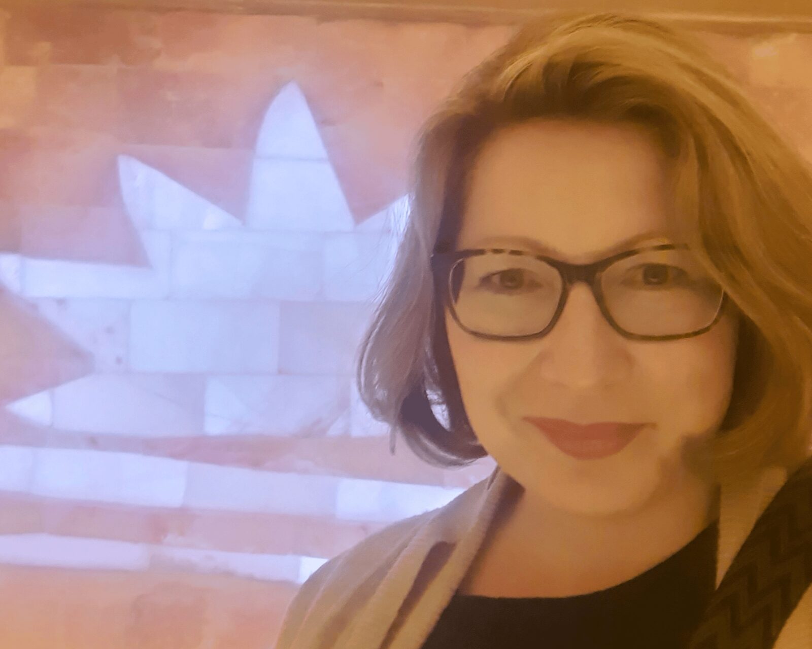 Kerstin Hiemer lächelt in der Salzgrotte, im Hintergrund die beleuchtete Salzwand