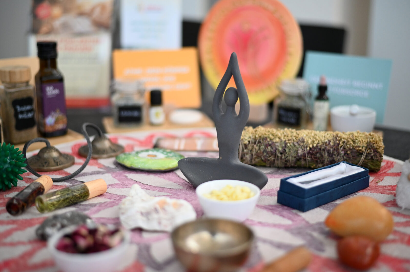 Stimmungsvolles Stillleben mit Yoga-Figur, Klangschale und Kräuterbund auf einem Messestand